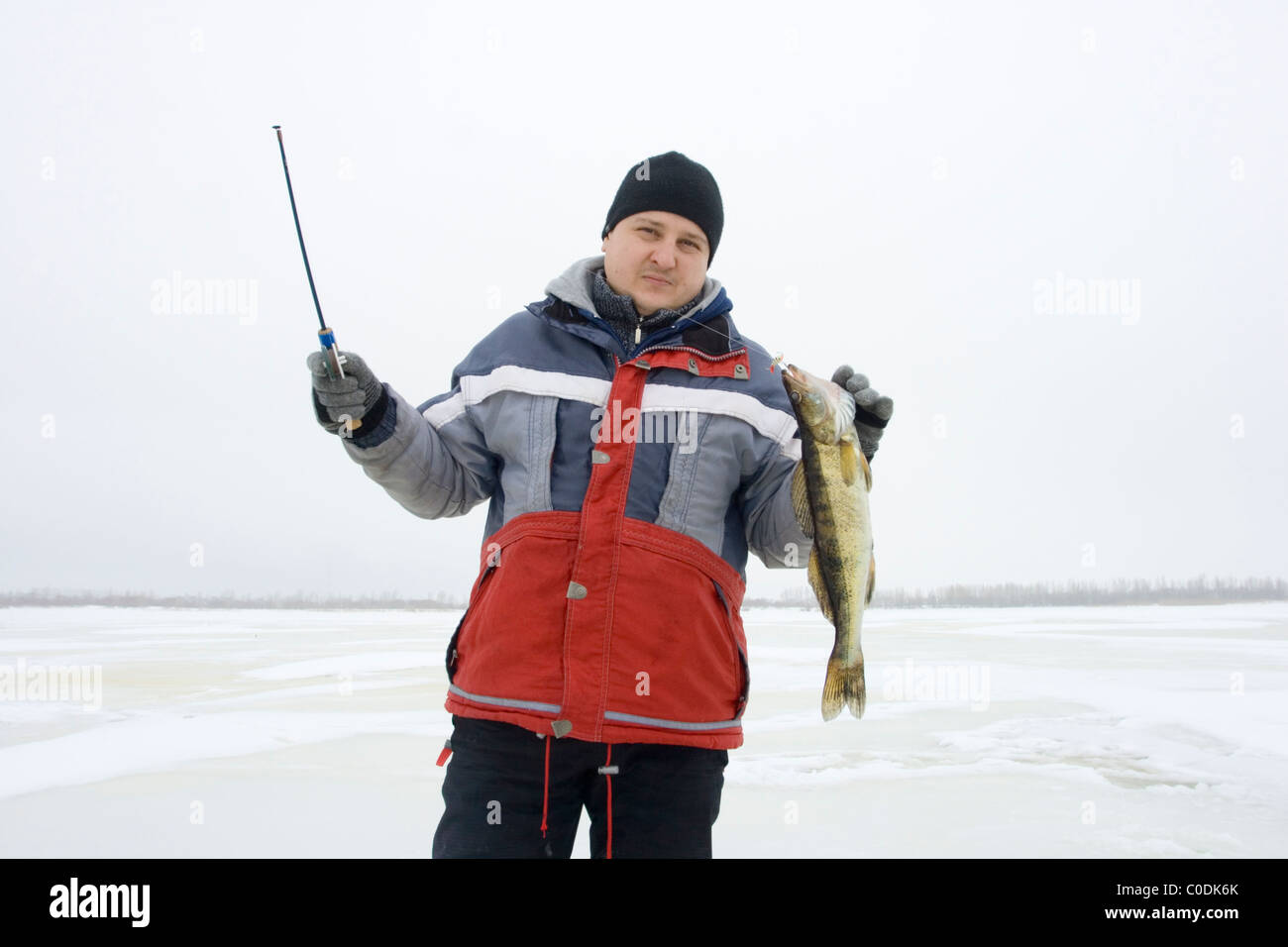 La pêche sur glace en hiver. Le pêcheur de poissons un trou de glace Banque D'Images