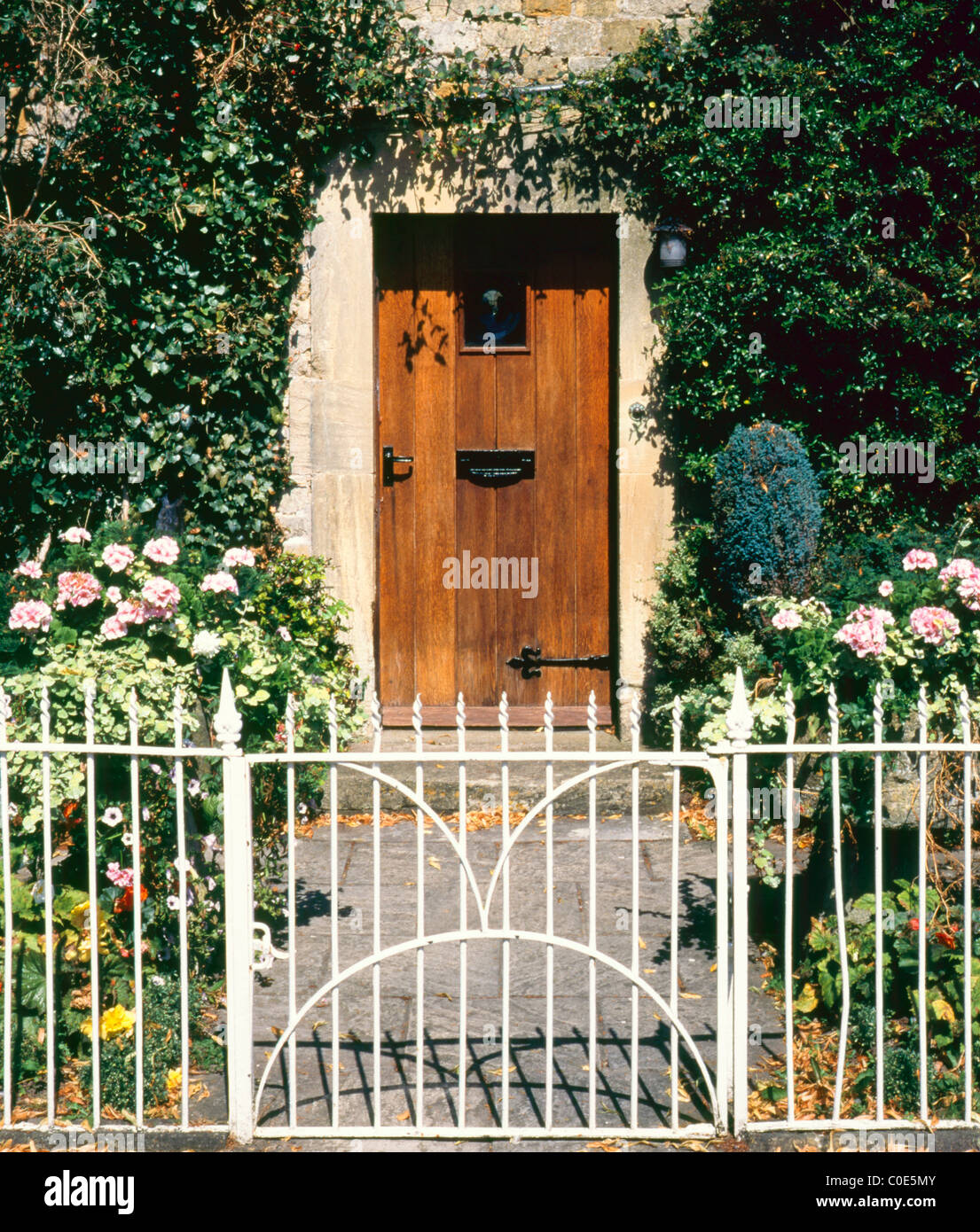 Porte de jardin en fer forgé fermé clôture et menant à une porte d'entrée  entourée de plantes grimpantes Photo Stock - Alamy