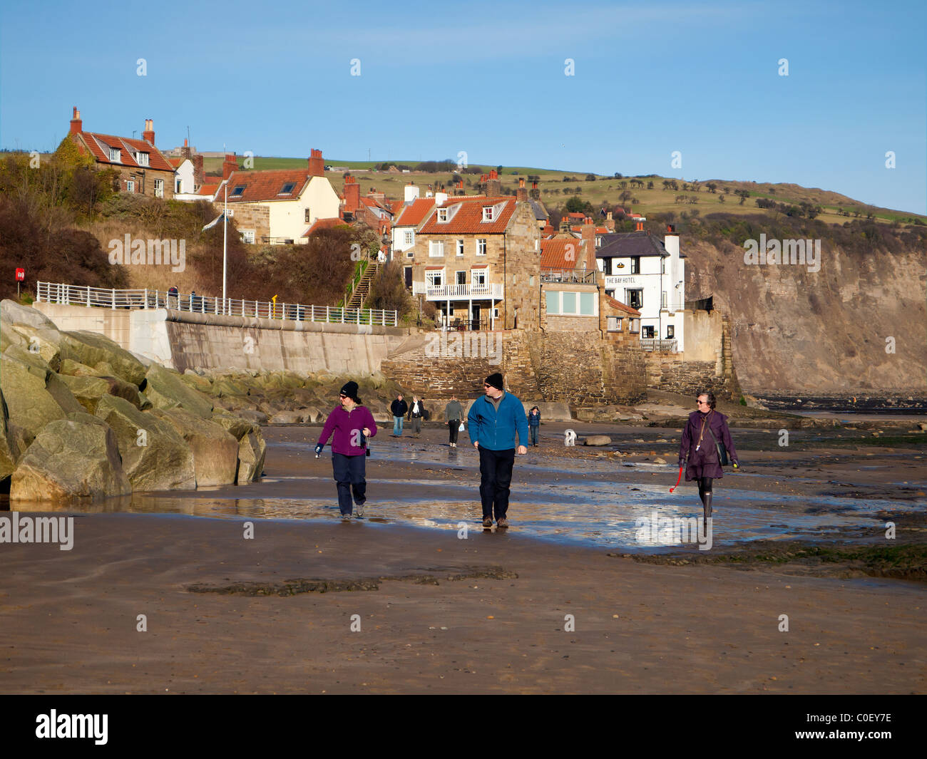Les gens qui marchent sur la plage de Robin Hood's Bay North Yorkshire sur un jour d'hiver ensoleillé Banque D'Images