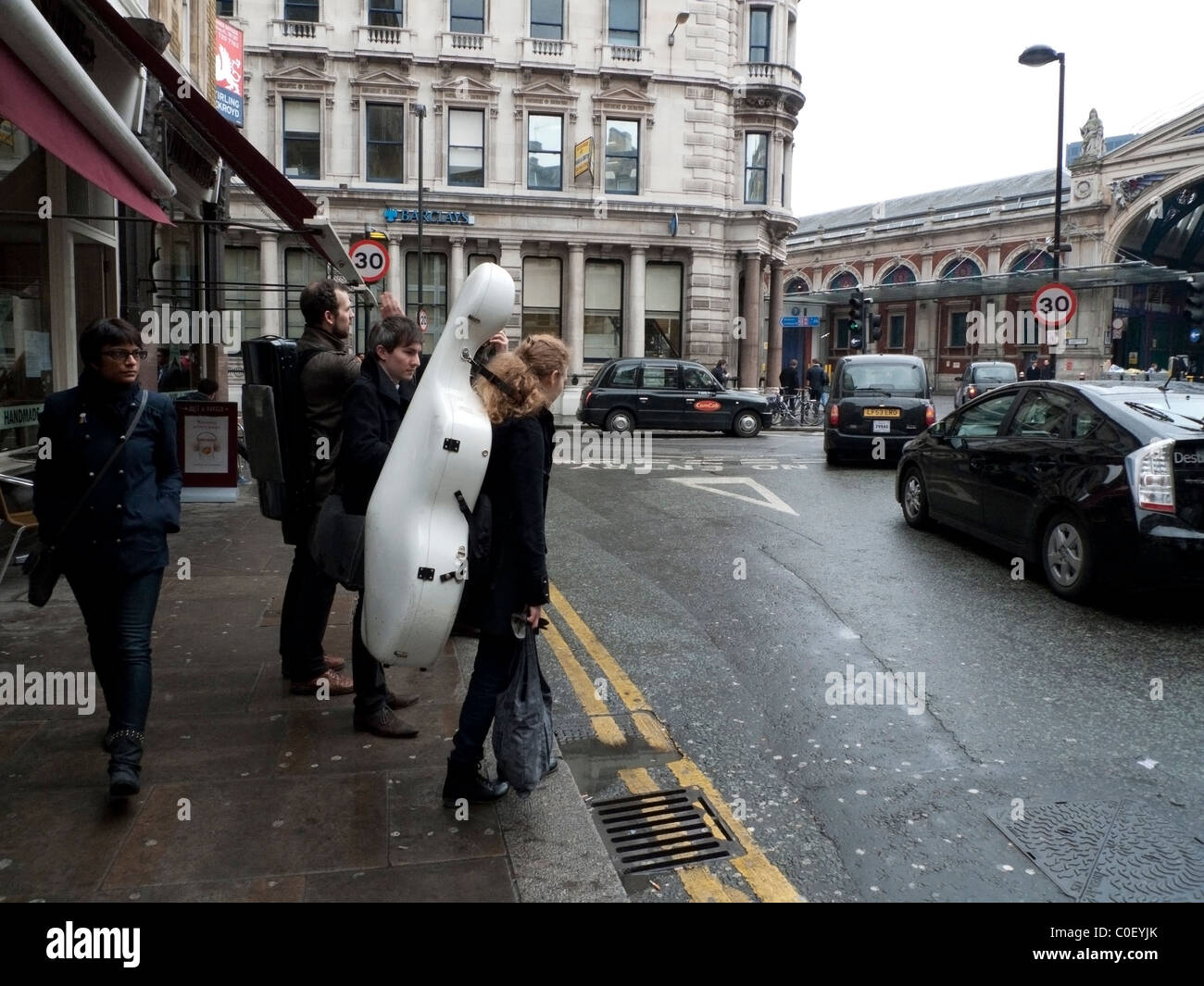 Une musicienne qui traverse Cowcross Street près de St John Street Et Smithfield Market Building portant un instrument de musique sur elle De retour en hiver à Smithfields City de Londres, Angleterre, Royaume-Uni KATHY DEWITT Banque D'Images