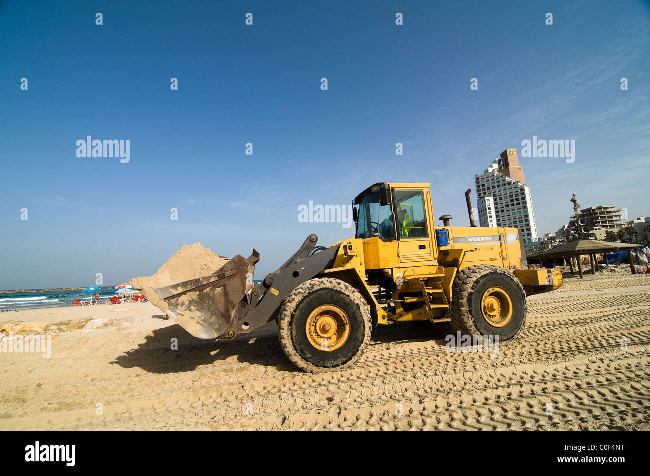 Un earth mover à une vague de construction coupe-site sur la plage de Tel Aviv. Banque D'Images