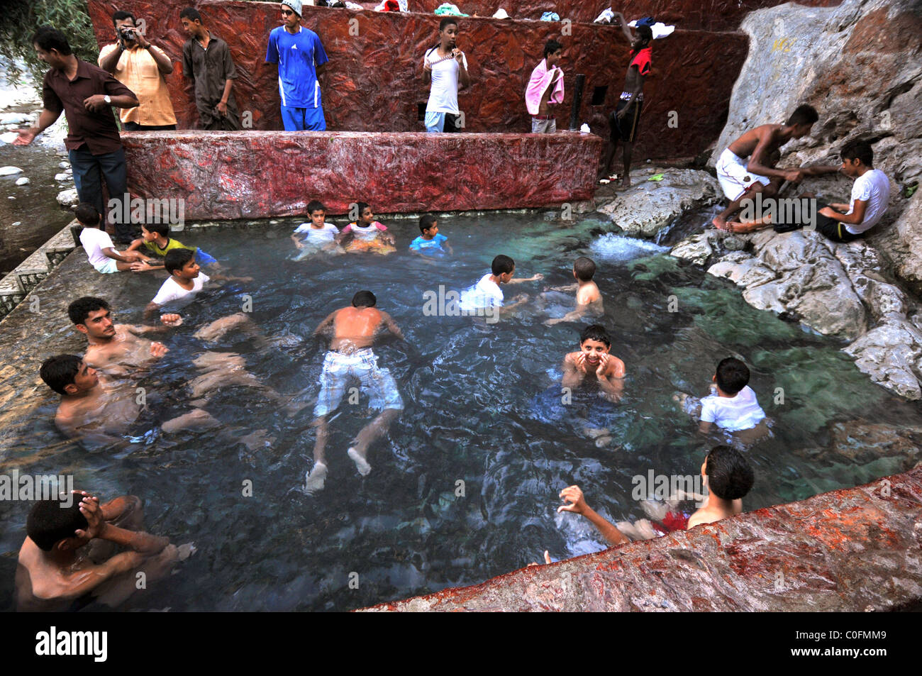 Les jeunes se baigner dans la source d'eau chaude à Nakhal. Le Sultanat d'Oman. Banque D'Images