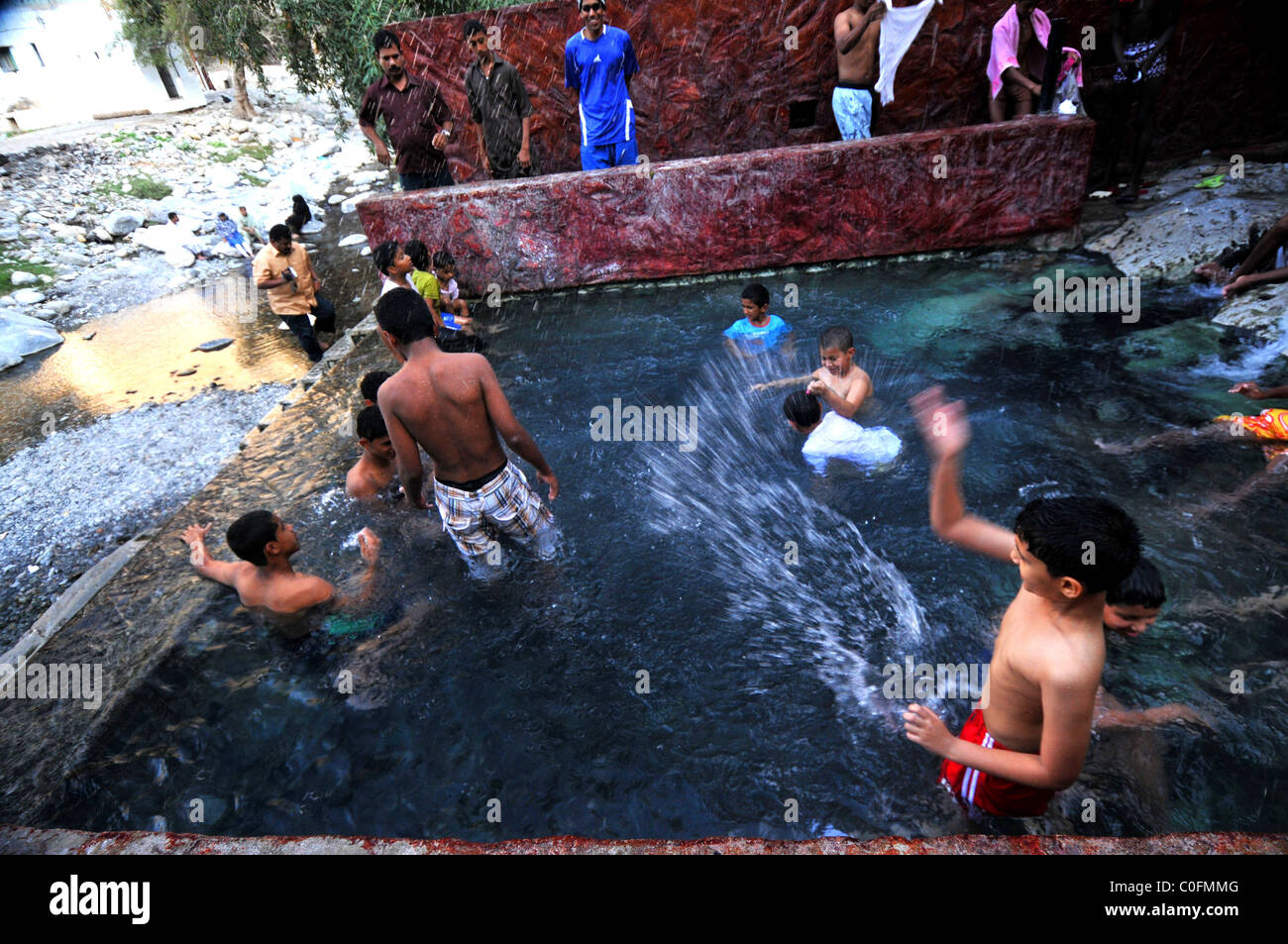 Les jeunes se baigner dans la source d'eau chaude à Nakhal. Le Sultanat d'Oman. Banque D'Images