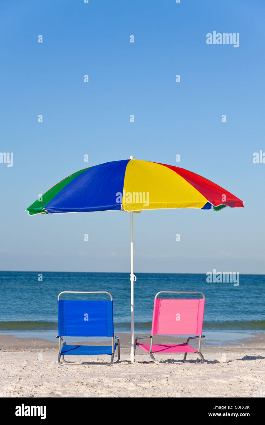 Rose et bleu chaises longues sur une plage sous un parapluie ou parasol coloré Banque D'Images