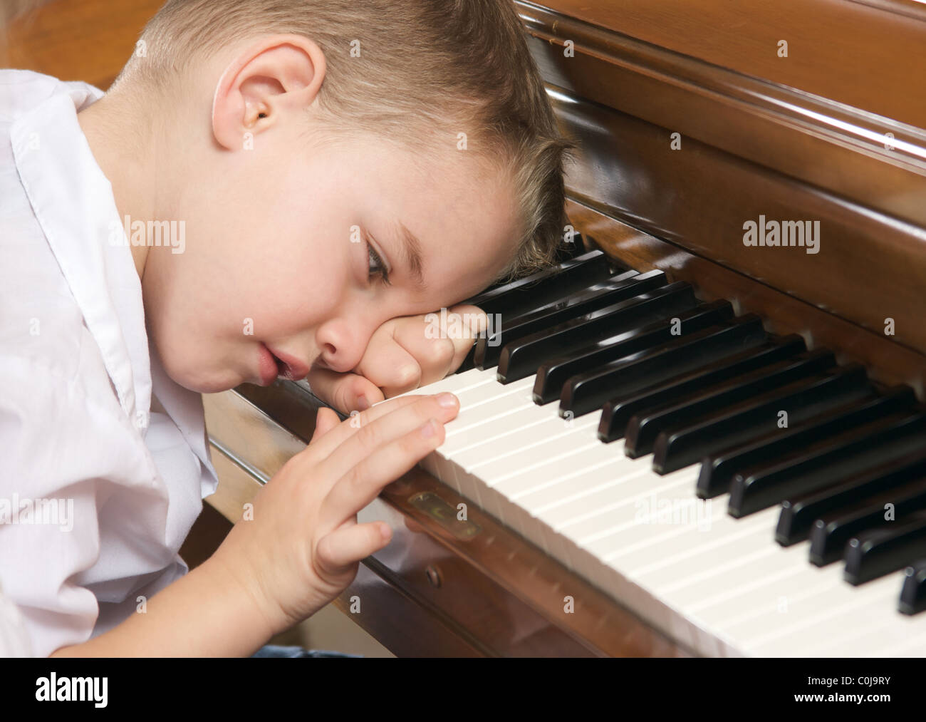 Jeune garçon triste avec la tête sur le Piano Photo Stock - Alamy