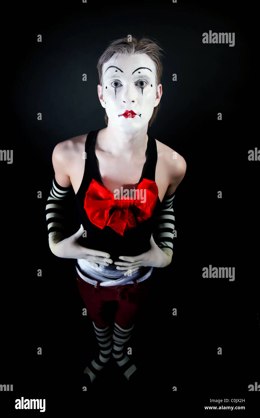 Studio portrait of theatrical funny clown avec un gros noeud sur la poitrine rouge sur fond noir Banque D'Images