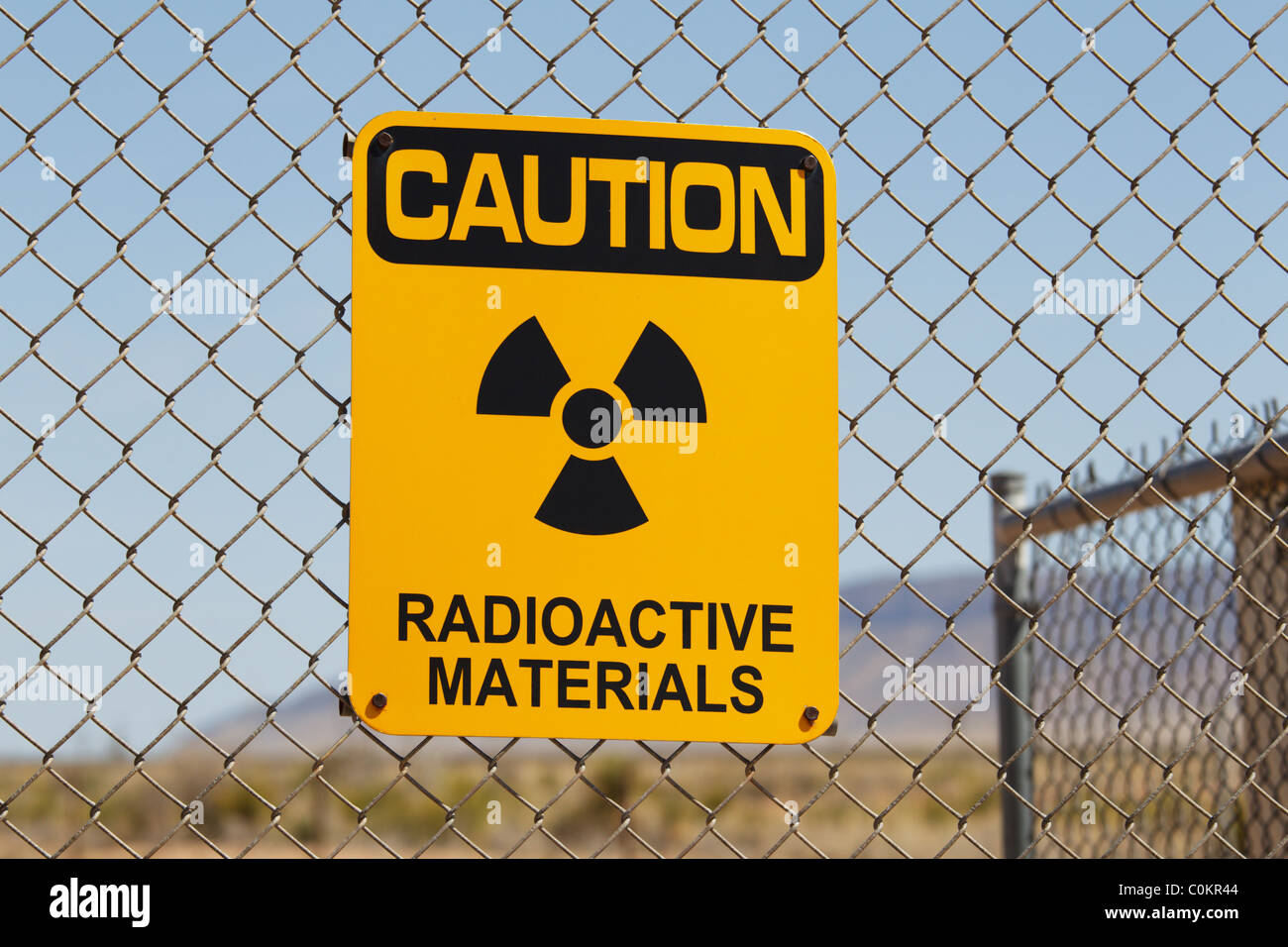 Un signe d'avertissement sur les matières radioactives sur une clôture métallique au site Trinity, Nouveau-Mexique. Banque D'Images