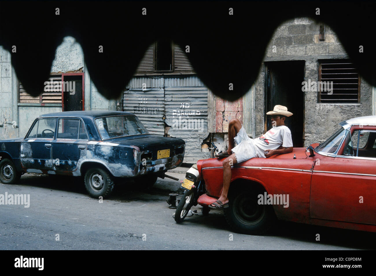 La Havane. Cuba. L'homme posé sur le capot d'une voiture américaine vintage dans Centro Havana. Banque D'Images