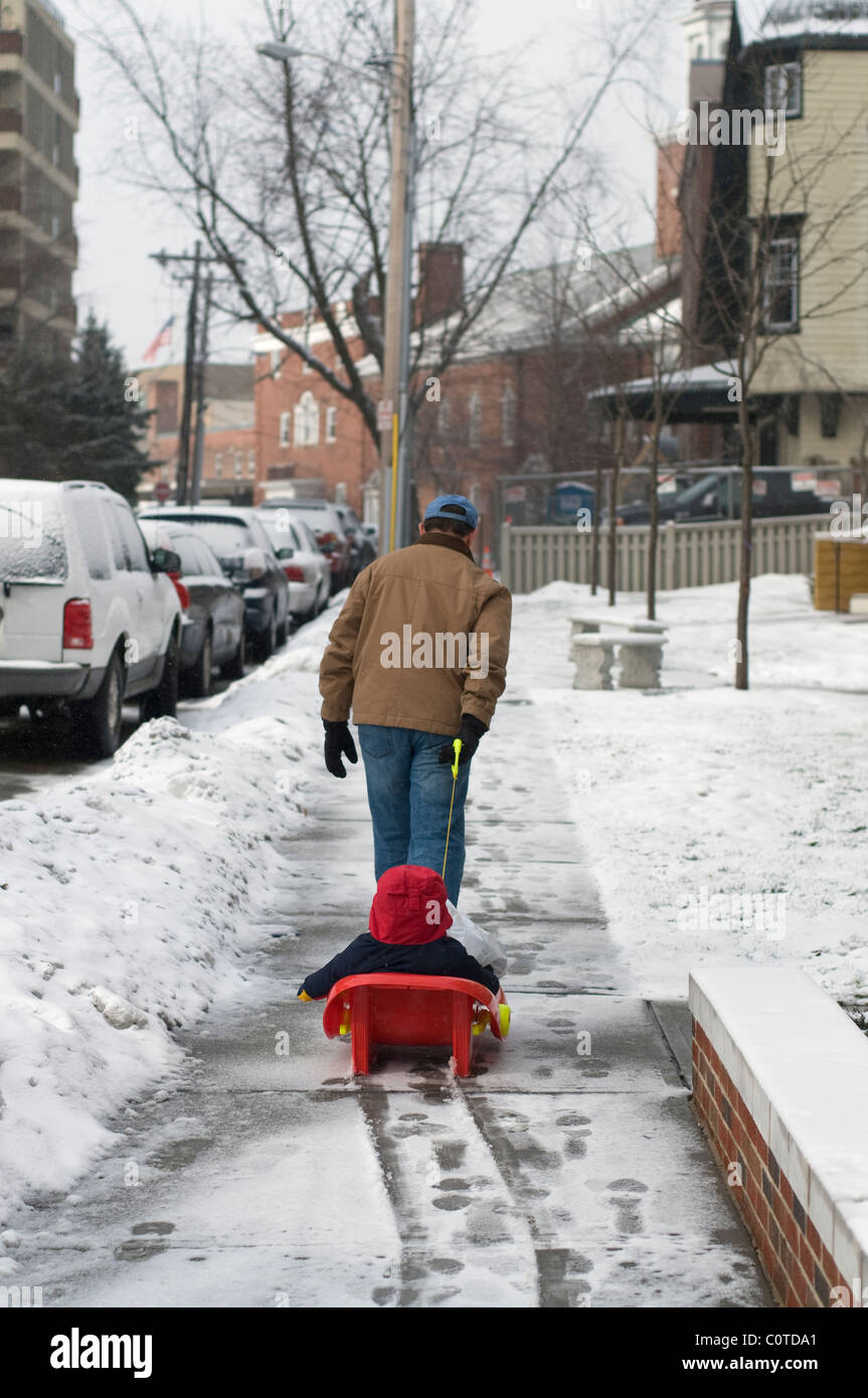 Un père en faisant glisser son fils dans un traîneau après une mince couche de neige à Boston MA. Banque D'Images