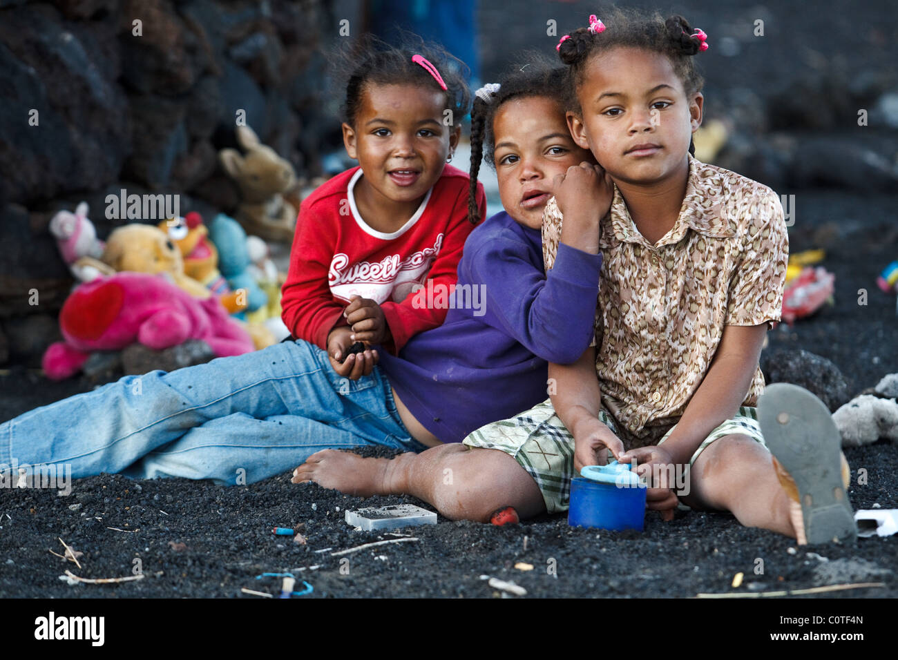 Trois jeunes filles s'asseoir sur le sol tout en prenant une pause de jouer avec les animaux en peluche dans cha de Caldeiras, île de Fogo Banque D'Images