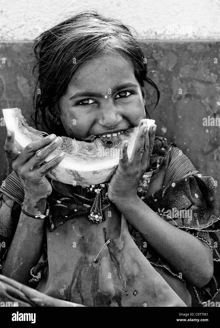 Heureux jeunes pauvres caste inférieure Indian street girl eating une tranche de pastèque. Monochrome Banque D'Images