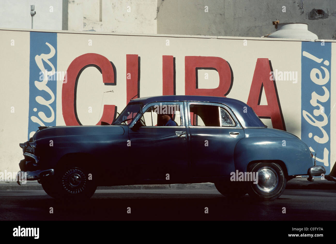 La Havane. Cuba. American Vintage voiture en face de slogan patriotique 'Viva Cuba Libre' dans la vieille Havane. Banque D'Images