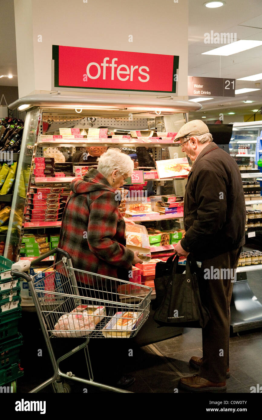 Un vieux couple de personnes âgées qui magasinent pour de la nourriture dans la section « Offres » d'un restaurant Marks and Spencer, Kent, Royaume-Uni Banque D'Images