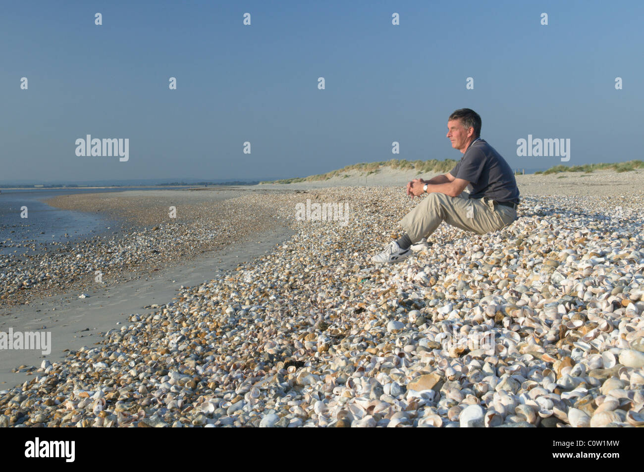 L'homme personne assise sur coquilles massés sur le bord ouest de la tête de l'Est, l'ouest wittering, West Sussex, UK. septembre. Banque D'Images