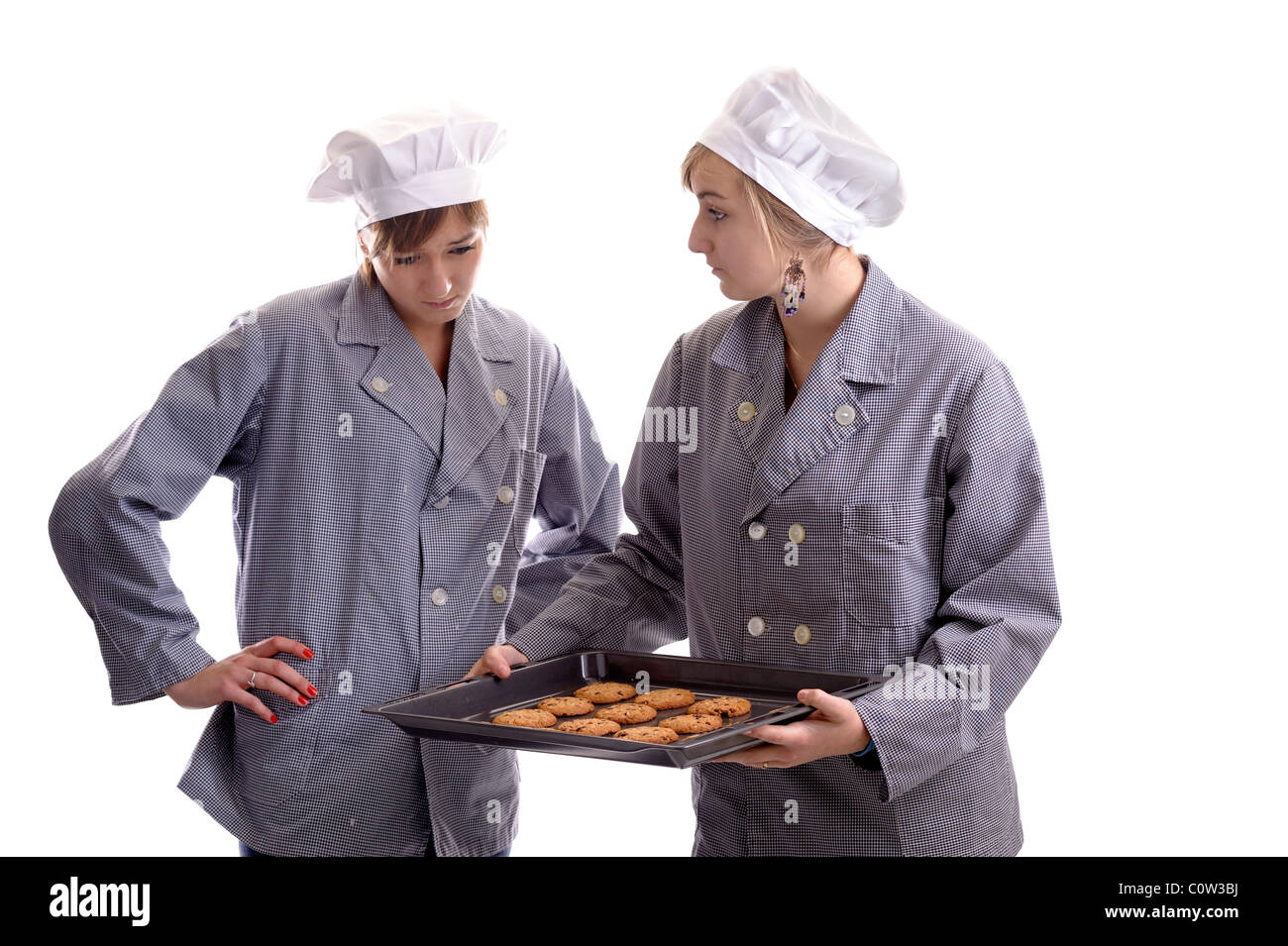 Deux jeunes cuisiniers en vêtements cook l'inspection des cookies sur une plaque. isolated on white Banque D'Images
