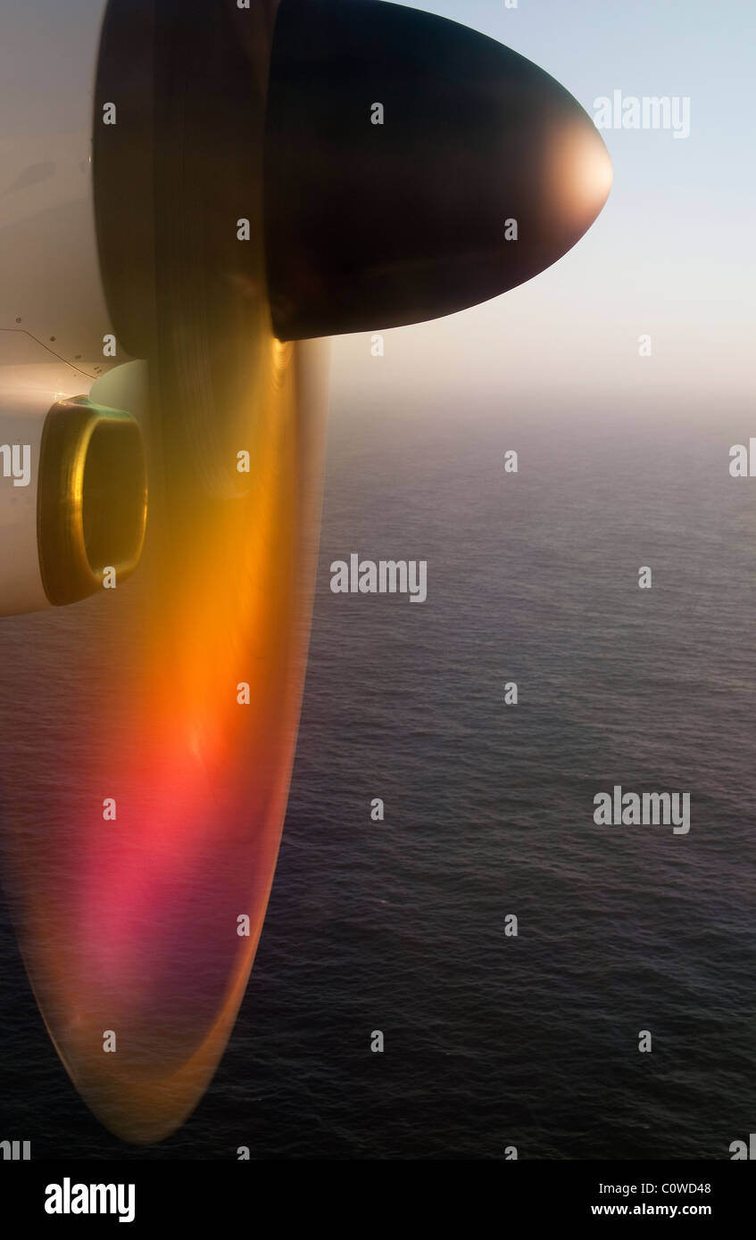 Moteur d'avion turbopropulsé réfléchissant la lumière du coucher du soleil tout en descendant au-dessus d'une ville côtière dans les îles des Açores, au Portugal Banque D'Images