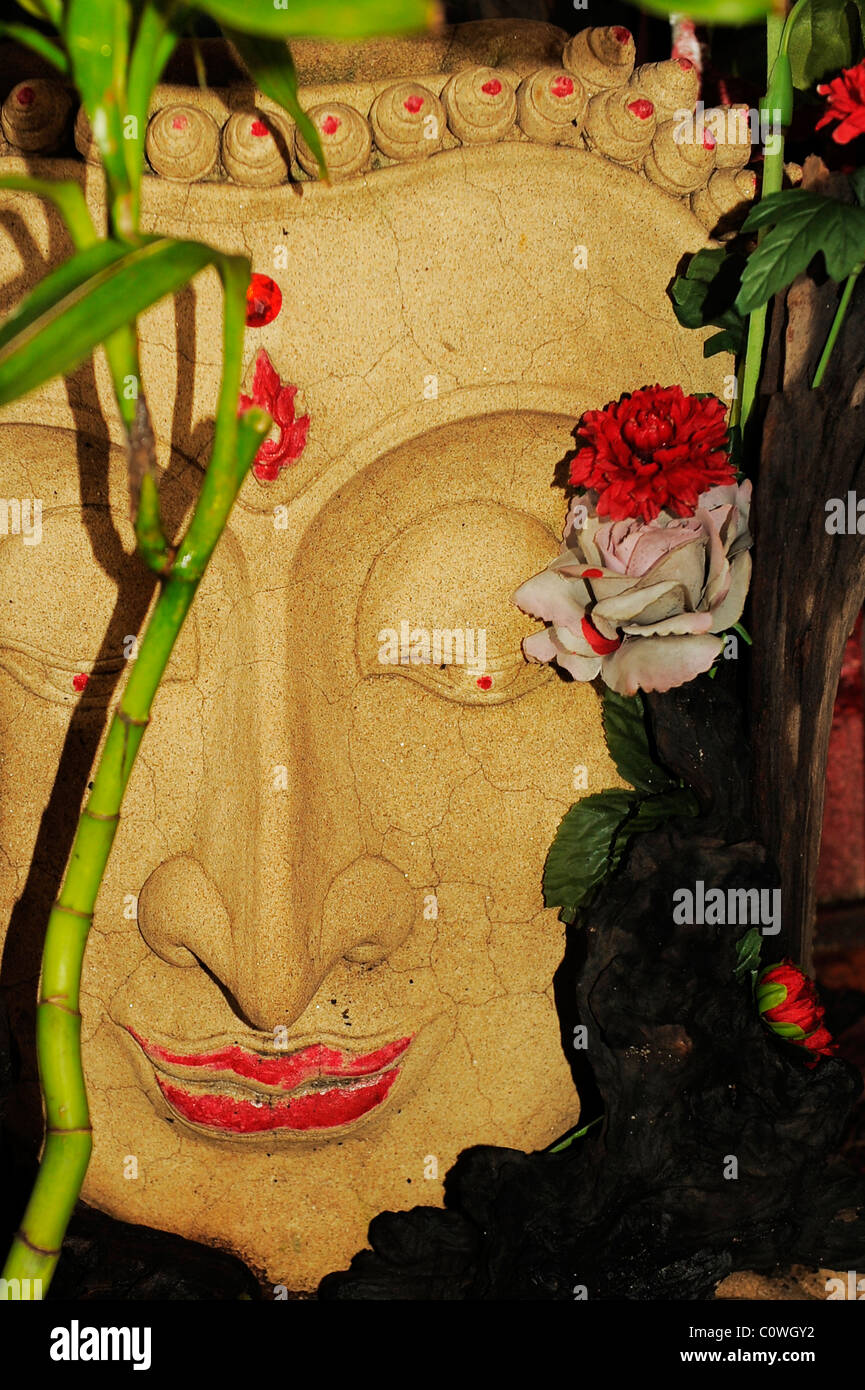 Image pierre bouddha décorées de fleurs , chinatown , Bangkok, Thaïlande Banque D'Images