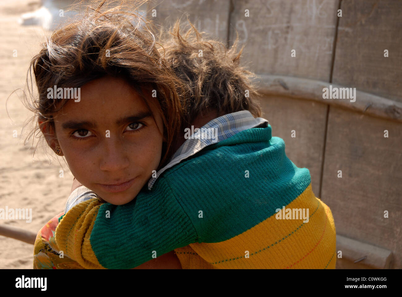 Jeune fille portant son petit frère d'une porte de son village du désert du Rajasthan en porte Banque D'Images
