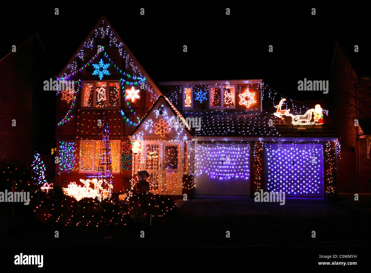 Les lumières de Noël de fête colorée et décorations qui recouvrent complètement l'extérieur de la maison et le jardin de banlieue. Banque D'Images