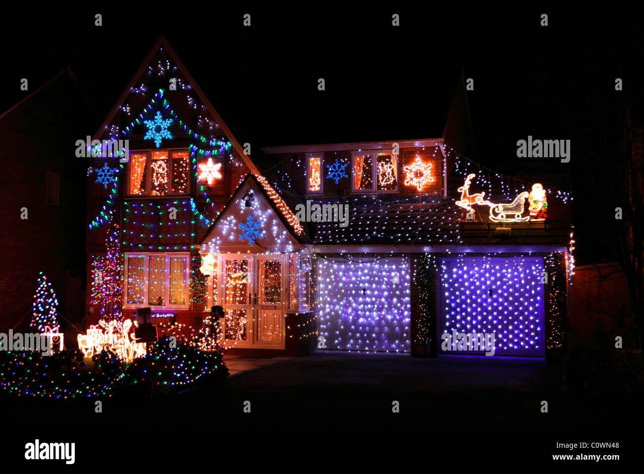 Les lumières de Noël de fête colorée et décorations qui recouvrent complètement l'extérieur de la maison et le jardin de banlieue. Banque D'Images