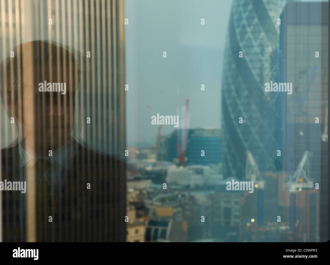 Reflet de l'homme d'affaires dans la fenêtre avec la vue du quartier de la city de Londres en arrière-plan Banque D'Images