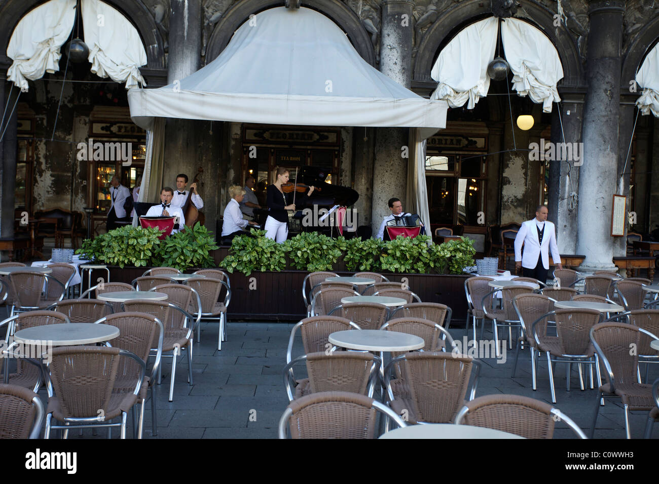 Un groupe jouer à l'un des restaurants sur la Place St Marc Piazza dans une tentative de gagner des affaires. Tables vides à l'avant-plan. Banque D'Images