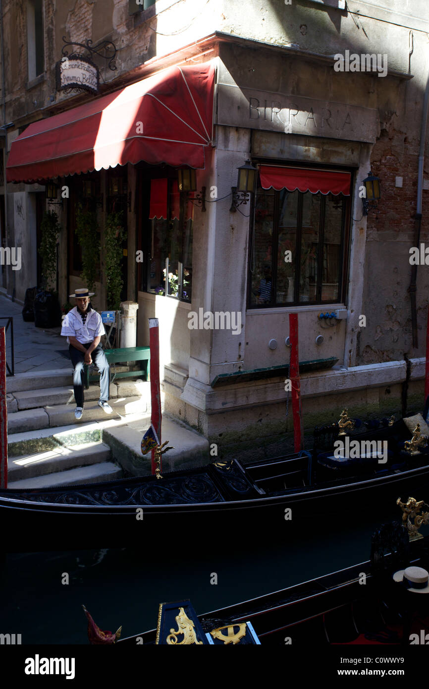 Un gondolier est assis à côté de son personnalisé attendent en gondole Venise Italie Banque D'Images