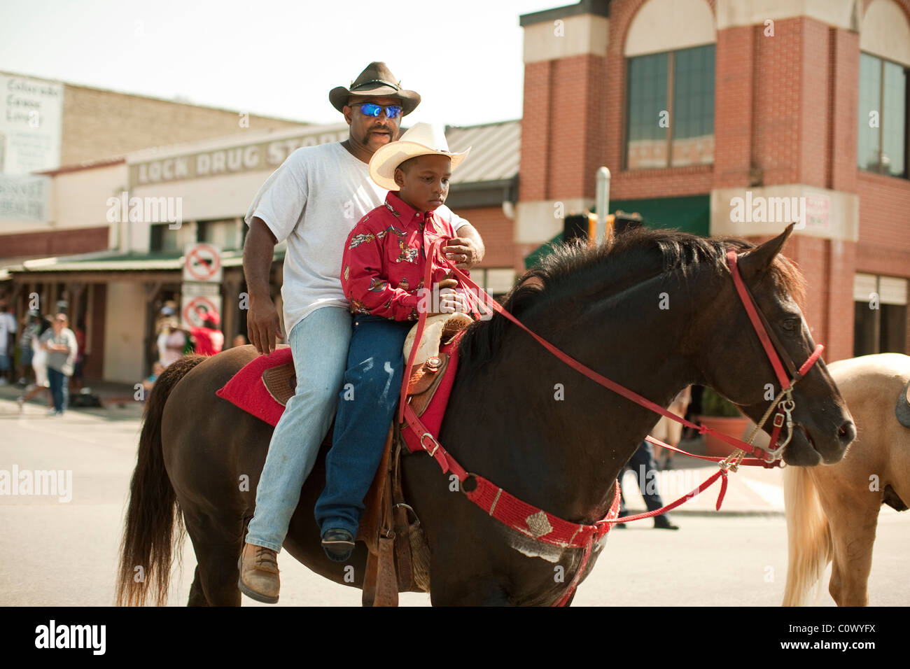 L'homme afro-américain et le garçon monter à cheval pendant un défilé pour célébrer Juneteenth au centre-ville de Brenham, Texas Banque D'Images