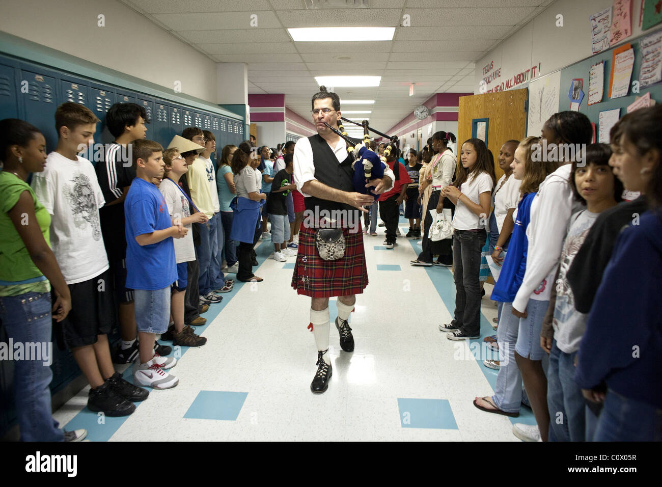 Joueur de cornemuse en kilt homme démontre l'instrument dans le couloir à Park Crest Middle School au cours de la Journée de la diversité Banque D'Images