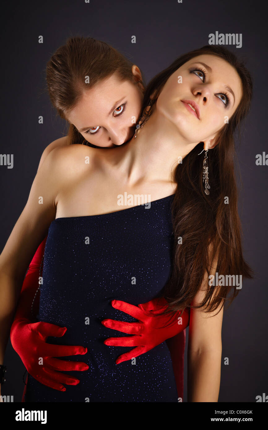 Deux jeunes filles qui dépeint le vampire et son sacrifice sur fond sombre Banque D'Images