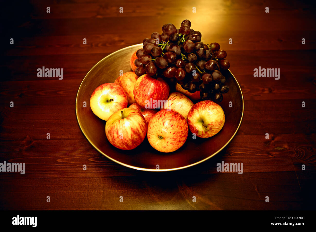Bol de pommes et raisins sur table en bois Banque D'Images