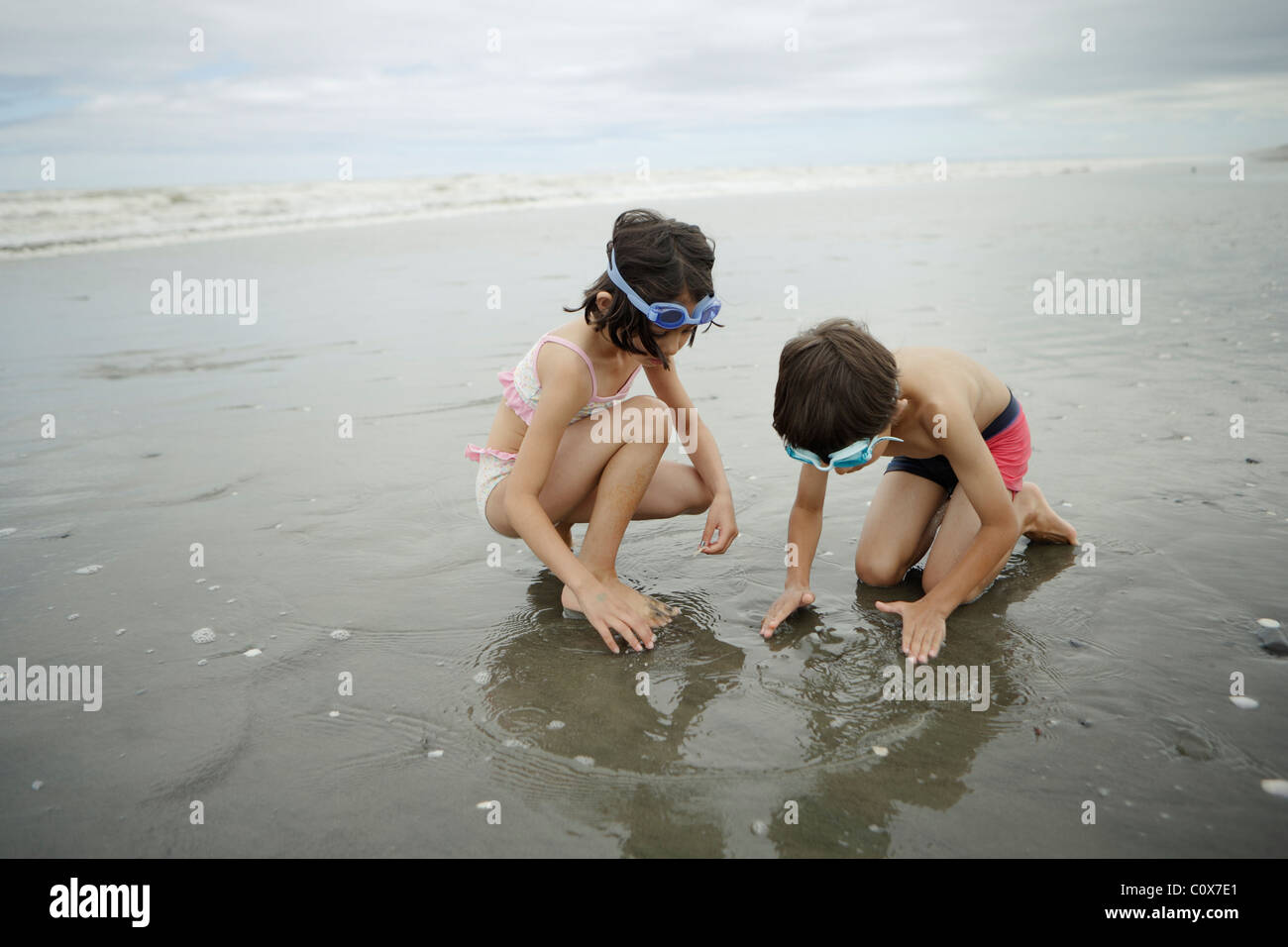 Frère et sœur, mixed race, jouer dans la mer. Manawatu, Nouvelle-Zélande. Banque D'Images