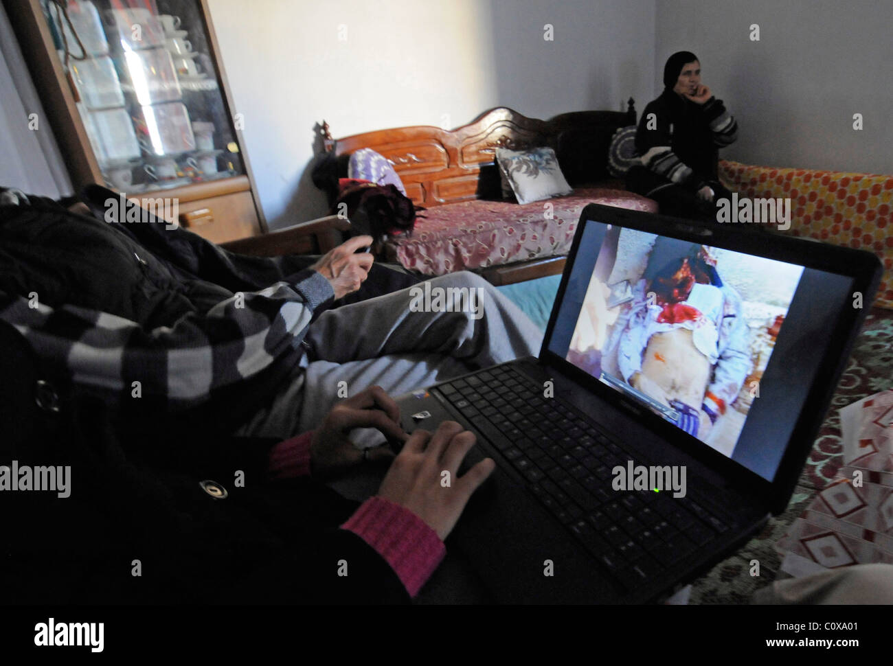 Une famille tunisienne regarder la vidéo sanglante des manifestations et des affrontements posté sur Facebook pendant la révolution de jasmin pendant un couvre-feu. Banque D'Images