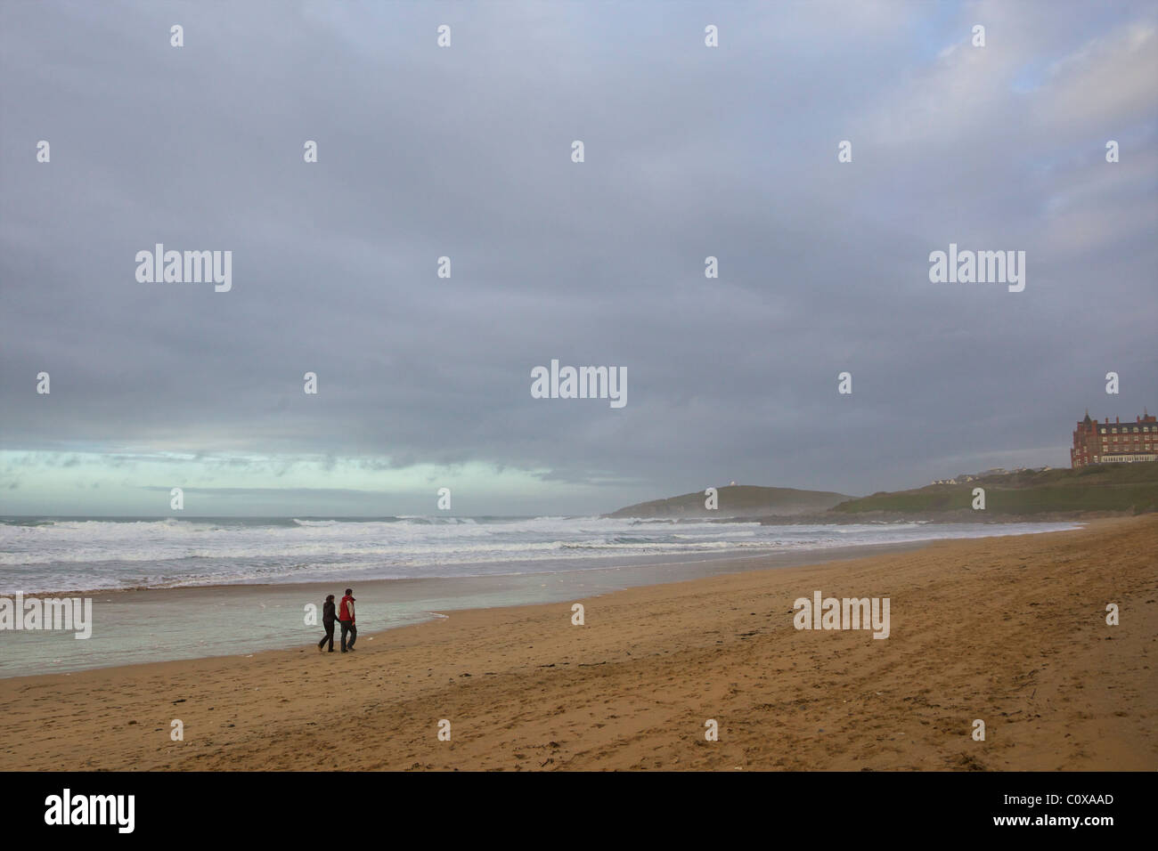 Jeune couple en train de marcher, d'hiver surf, plage de Fistral, Newquay, Cornwall, Angleterre du Sud-Ouest, Royaume-Uni, Royaume-Uni, GO, Grande-Bretagne, Banque D'Images