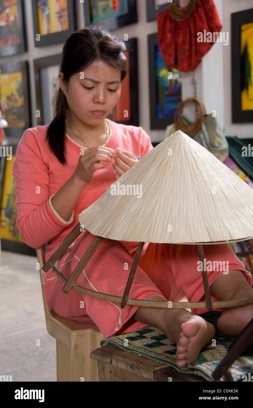 L'Asie, Vietnam, Da Nang. Ancienne capitale impériale de Hue. Woman making local vietnamien typique en forme de chapeaux coniques en bambou. Banque D'Images