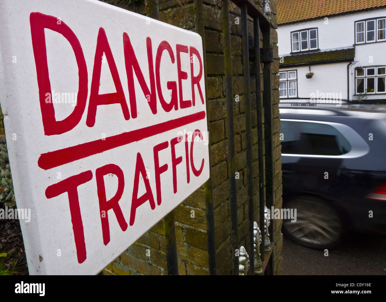 Un panneau d'avertissement "Danger" Lecture de la circulation avec une voiture en mouvement sur la route derrière Banque D'Images