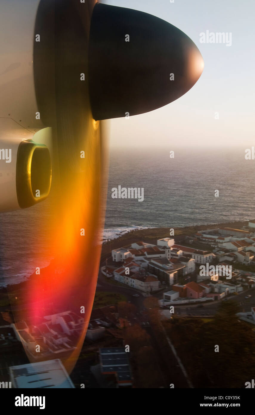 Moteur d'avion turbopropulsé réfléchissant la lumière du coucher du soleil tout en descendant au-dessus d'une ville côtière dans les îles des Açores, au Portugal Banque D'Images