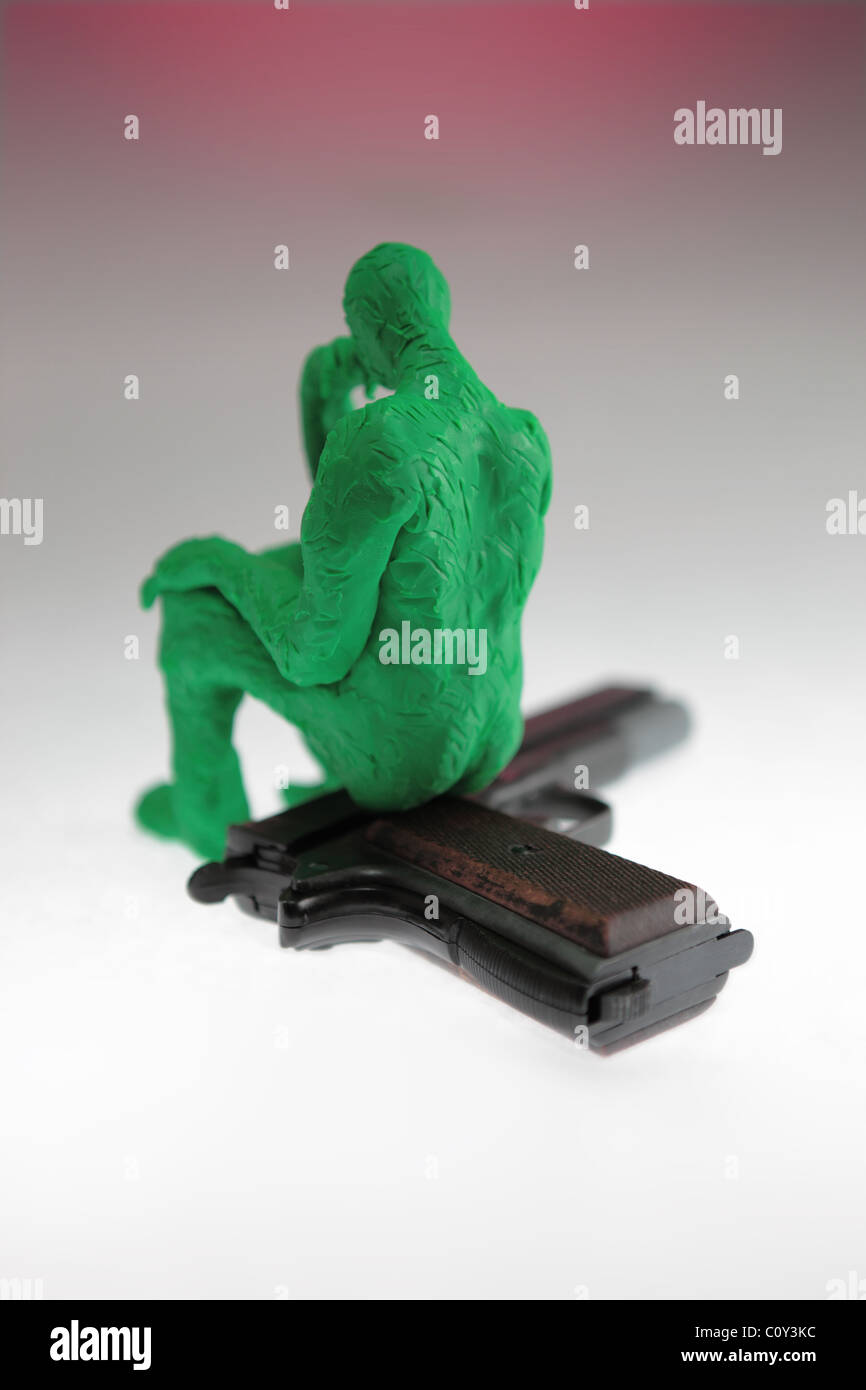 Une figurine en argile à modeler représentant un homme assis sur un fusil. L'homme pense à quelque chose de terrible. Banque D'Images