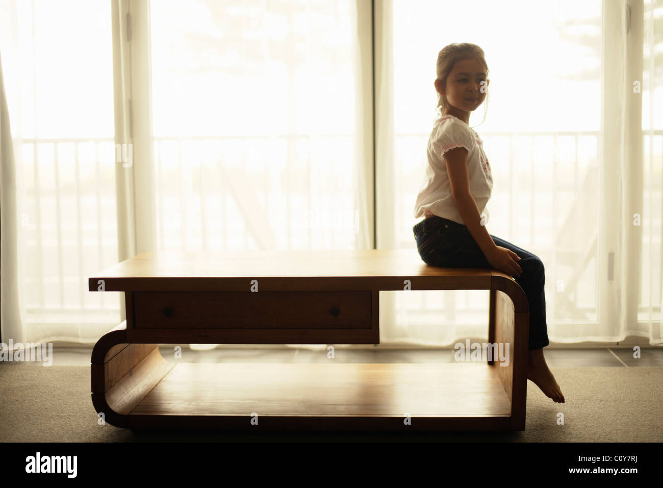 Fille est assise sur la fenêtre à côté de la table Banque D'Images