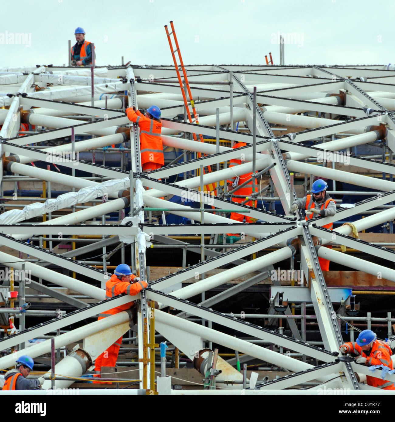 Équipe de travailleurs de l'industrie de la construction de sites de haute visibilité veste casques de sécurité occupés à travailler sur la nouvelle partie de toit de la station Kings Cross Londres Angleterre Royaume-Uni Banque D'Images