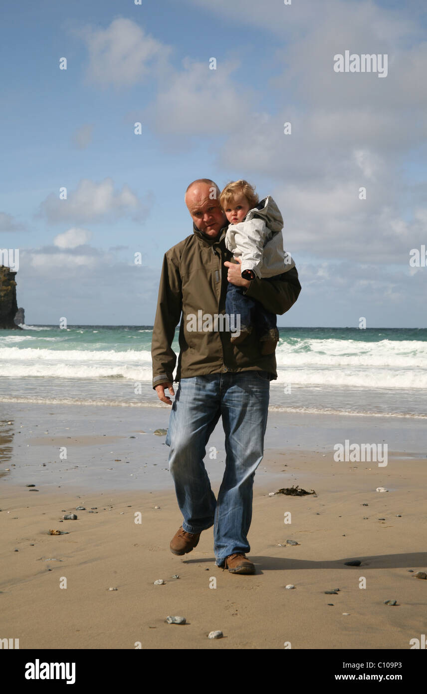 Père avec petit enfant marcher vers la caméra sur la plage Banque D'Images