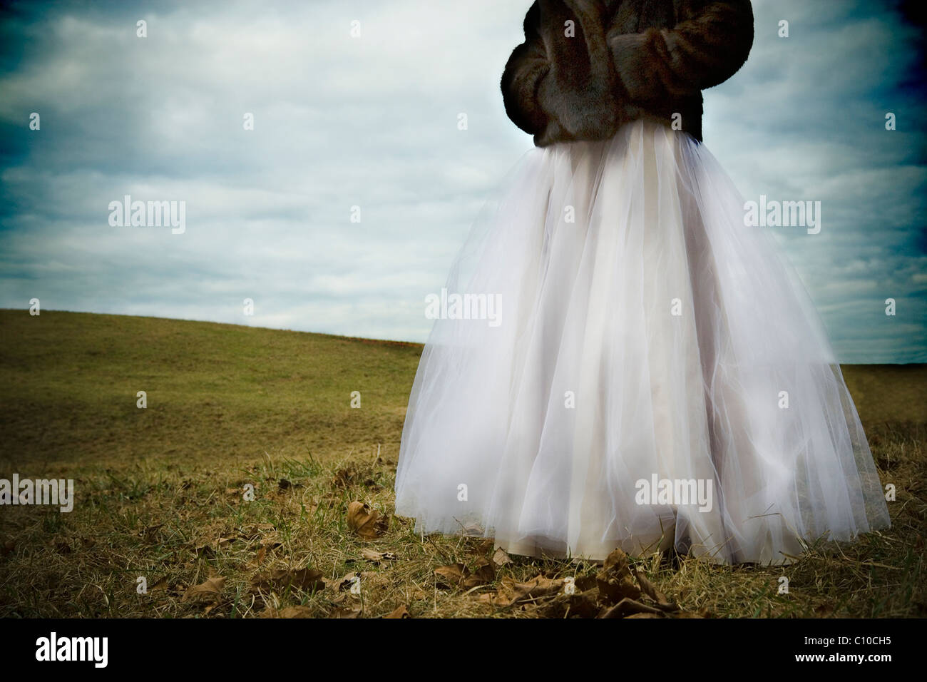 Une adolescente se trouve dans un champ Virginie vêtu de blanc robe de bal et manteau de vison. Banque D'Images