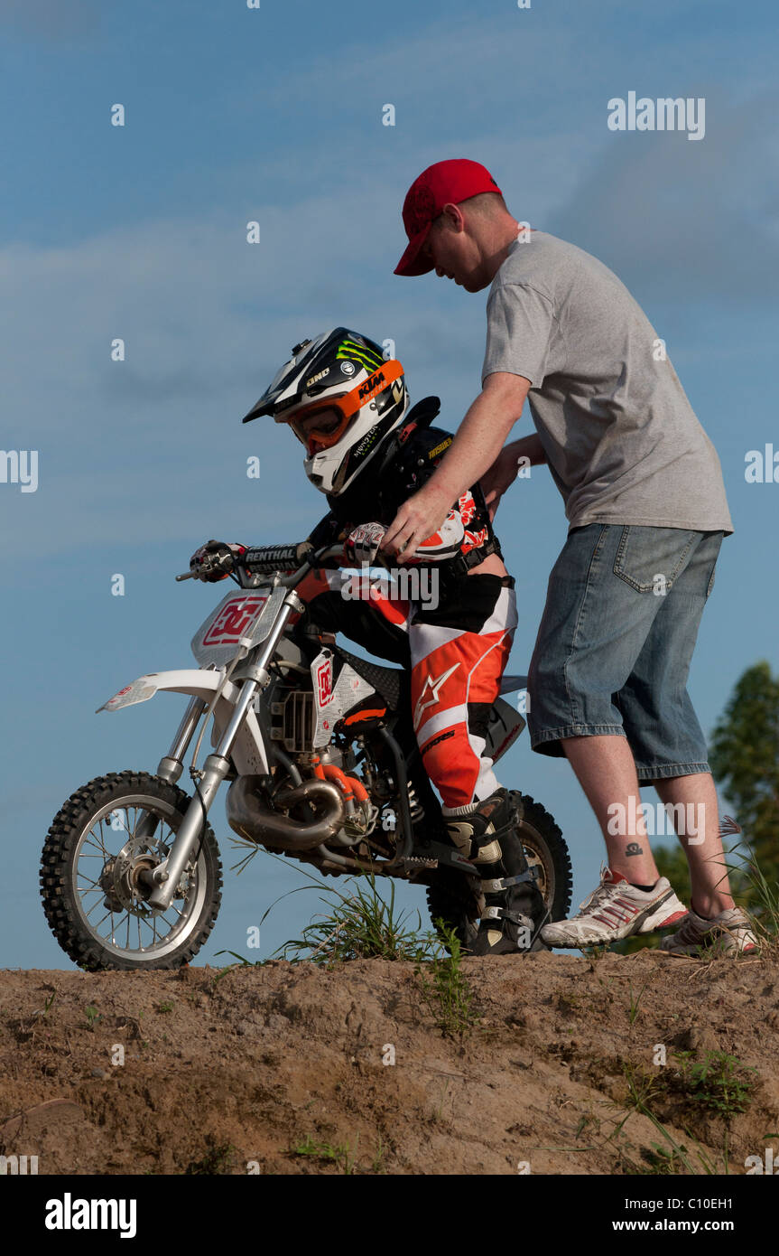 Un garçon de six ans avec son père et motocross bike Banque D'Images