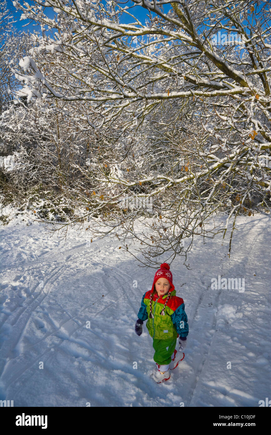 Petite fille qui marche dans la neige, Burghfield Common, Reading, Berkshire, Angleterre, Royaume-Uni, Europe Banque D'Images
