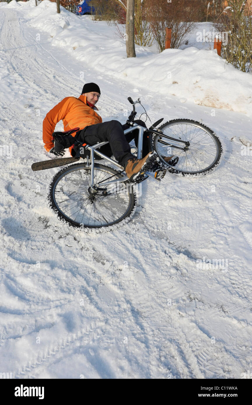 Un cycliste se brisant sur route glissante couverte de neige Banque D'Images