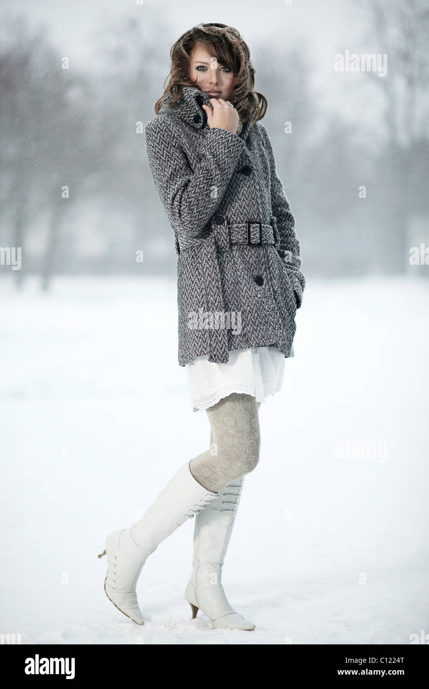 Portrait d'une jeune femme dans la neige, sa main tenant son collier manteau Banque D'Images