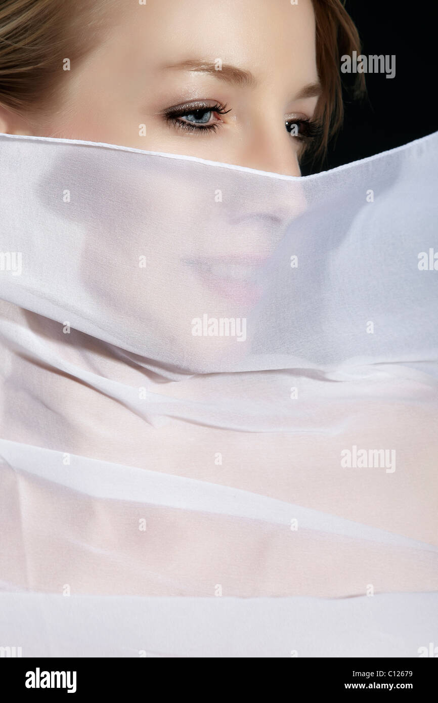 Portrait d'une jeune femme avec un tissu en soie blanche devant son visage Banque D'Images