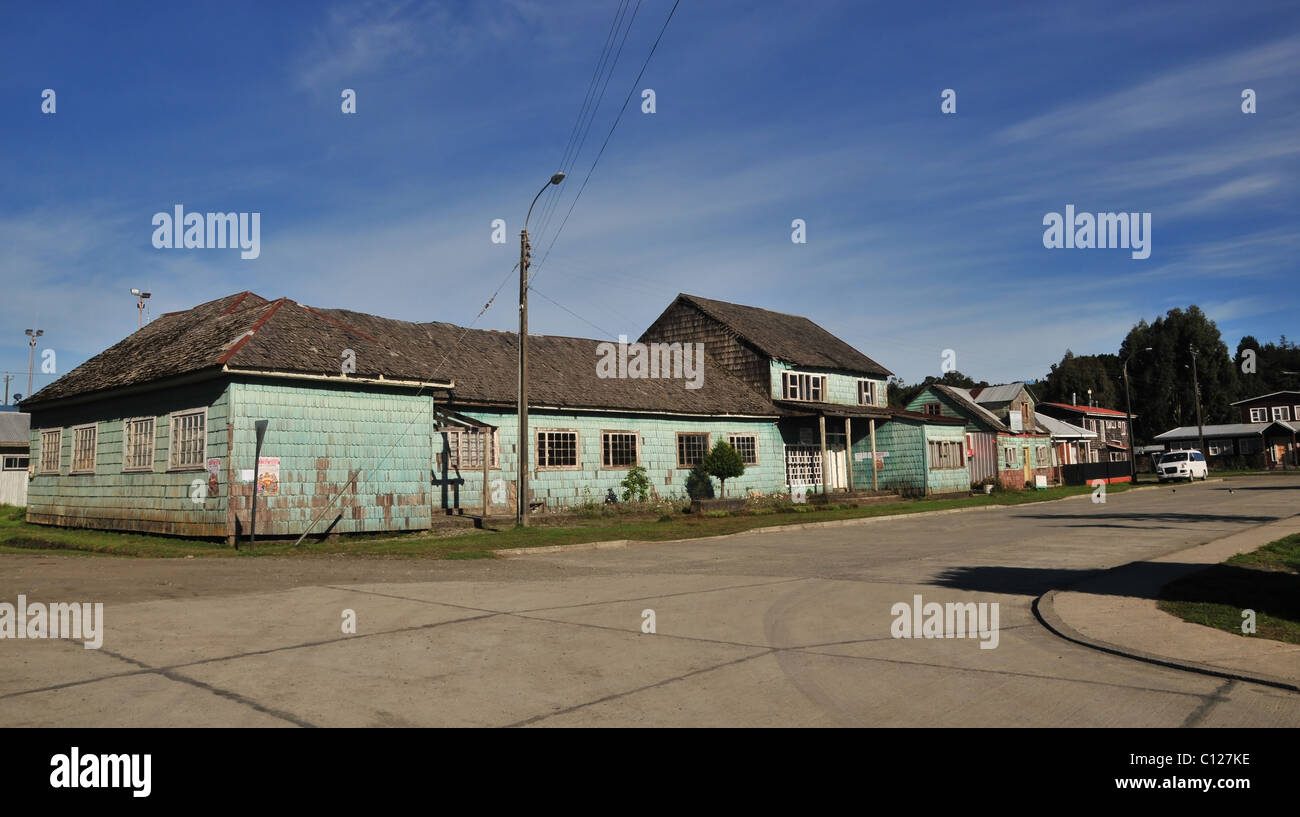 Vue du ciel bleu d'une rangée de maisons en bois, avec des murs de galets vert brun, bardeaux de toiture, Plaza Martin Ruiz, Chacao, Chiloé, Chili Banque D'Images