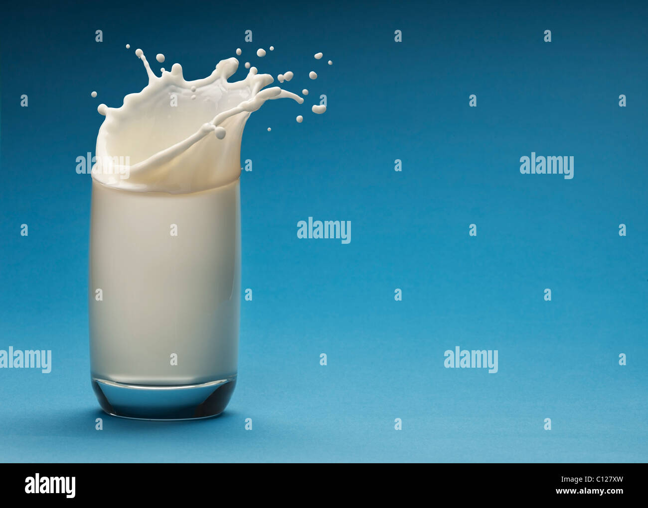 Nuage de lait dans le verre sur un fond bleu Banque D'Images