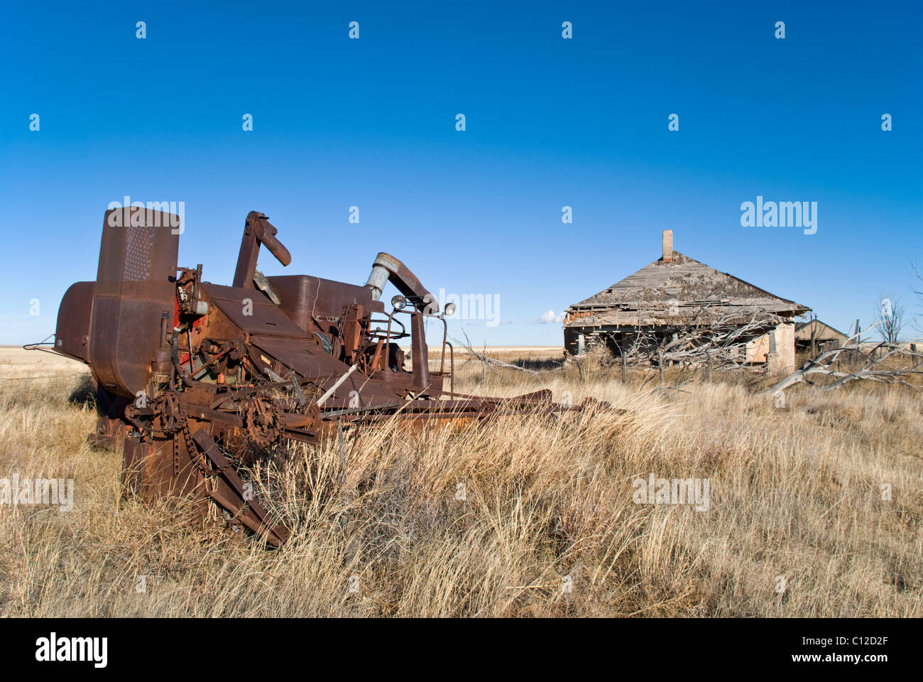 Rusty old farm machinery se trouve en face d'une maison abandonnée au Quay County, Nouveau Mexique. Banque D'Images